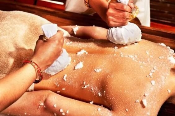 Spa exfoliation on a client's back, two therapists applying salt scrubs with cloths during a treatment