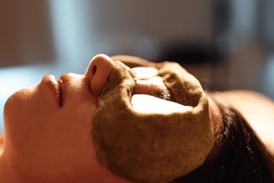 Person lying down during a spa facial with a clay mask on the cheeks.