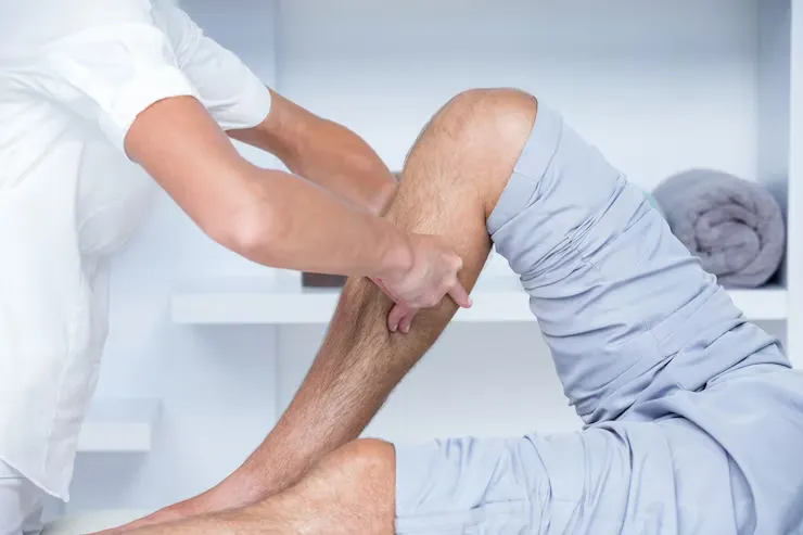 Physiotherapist guiding a patient through a knee flexion exercise in a clinic session.